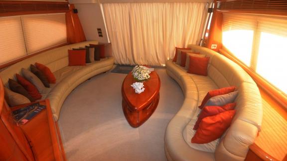 Inside the motor yacht Act, there is a spacious and comfortable seating area with elegant cushions and a coffee table.